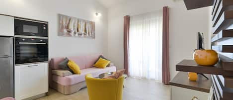 A modern living space with a kitchen, a sofa, a yellow chair, and a dining area with a shelf.