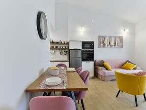 A modern kitchen with a refrigerator, oven, and microwave. There is a dining table with chairs and a sofa with cushions. - Holiday Apartment Inga Blue with exit to the beach by Interhome (Vir)