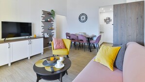 En moderne stue med sofa, sofabord, fjernsyn og spiseområde med stole og bord.