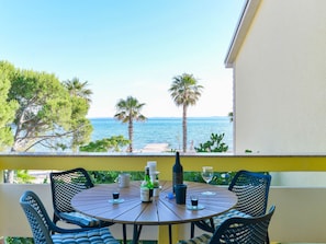 A round table with chairs, a bottle, and glasses on a balcony overlooking the sea. - Apartment  by Interhome (Vir)