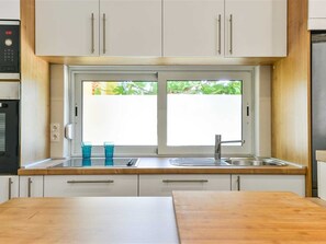 A kitchen with white cabinets, a double sink, and a window above the countertop. - Holiday Apartment Inga with exit to the beach by Interhome (Vir)