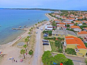 Eine Küstenstadt mit Strand, geparkten Autos und Wohnhäusern.
