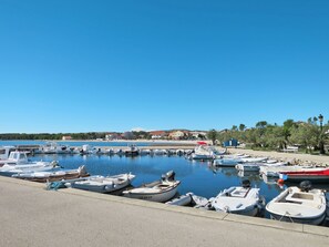 A marina with various boats docked, a clear blue sky, and buildings in the background. - Apartment  by Interhome (Vir)
