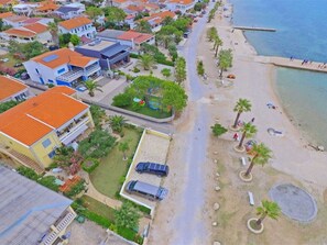 A coastal residential area with houses, a beach, and a road. - Apartment  by Interhome (Vir)