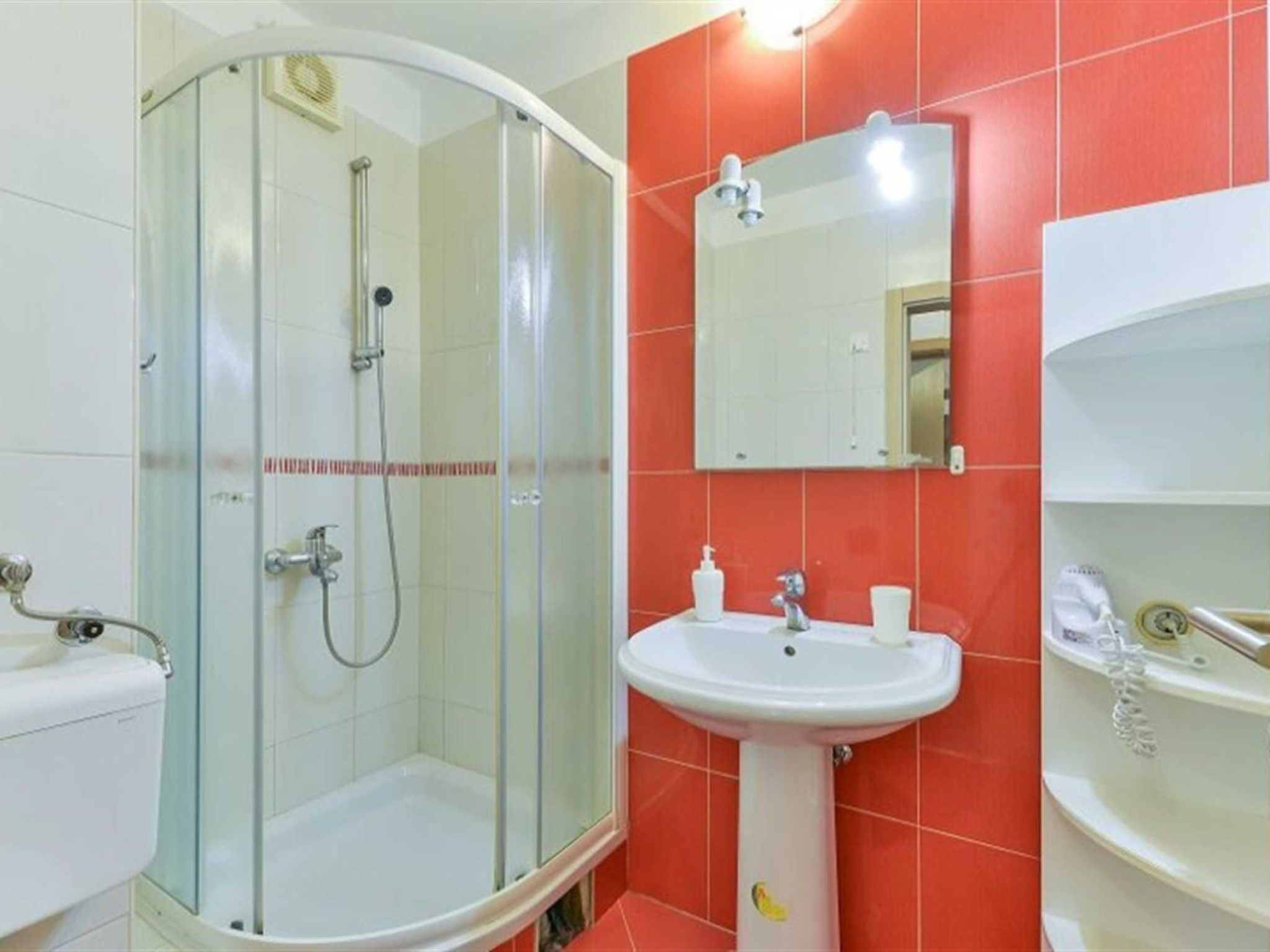 Un baño con ducha acristalada, lavabo y espejo.