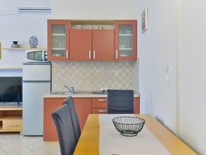 Una cocina compacta con microondas, estufa y comedor con mesa y sillas.
