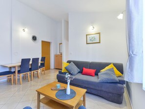 Ein modernes Wohnzimmer mit grauem Sofa, Esstisch aus Holz und Stühlen.
