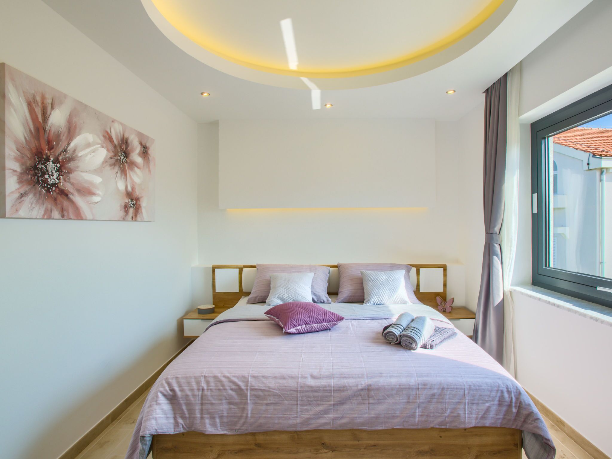 A modern bedroom with a wooden bed, a large window, and a ceiling light.