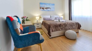 A hotel room with a bed, a chair, a painting, and a window with curtains. - Vacation home  by Interhome (Nin)