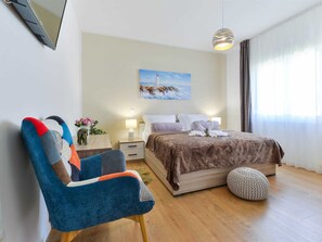 Ein Hotelzimmer mit einem Bett, einem Sessel, einem Gemälde und einem fenster mit Vorhängen.