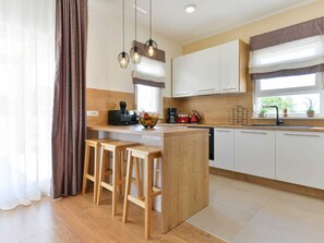 A modern kitchen with wooden countertops, a central island with stools, white cabinets, and pendant lighting. - Villa First Hill with heated pool by Interhome (Nin)