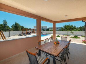 A covered patio with a pool, outdoor seating, and a dining table with chairs. - Villa First Hill with heated pool by Interhome (Nin)