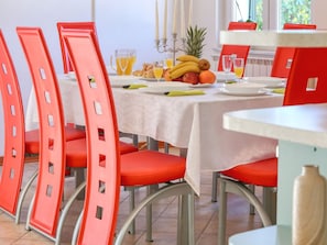 A dining area with red chairs and a table set for breakfast. - Villa Ana with large pool by Interhome (Policnik)