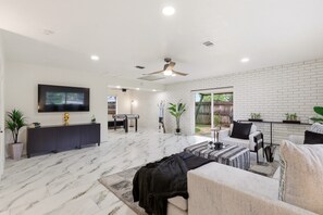 A modern living room with a marble floor, a ceiling fan, a flat-screen TV, and a seating area with a sofa and armchairs. - World Cup Villa · 7-Min Walk to AT&T Stadium (Arlington)