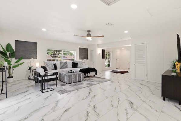 A spacious living room with a white ceiling, marble flooring, a sofa set, a coffee table, and a ceiling fan. - World Cup Villa · 7-Min Walk to AT&T Stadium (Arlington)