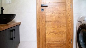 Uma porta de madeira com uma fechadura, uma máquina de lavar e um armário escuro com uma pia.