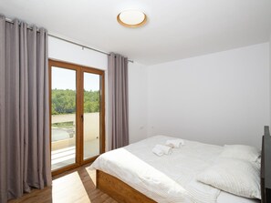 A bedroom with a bed, a window with curtains, a ceiling light, and a view of greenery outside. - Zen Garden Villa with heated pool by Interhome (Posedarje)