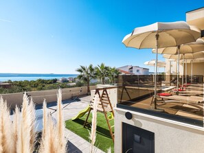 A modern outdoor patio with a view of the sea, a children's play area, and outdoor seating. - Villa Novue with pool by Interhome (Rovanjska)