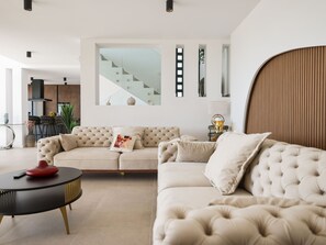 A modern living room with a beige sofa, a black coffee table, and a staircase in the background. - Villa Novue with pool by Interhome (Rovanjska)