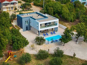 Uma casa moderna de dois andares com piscina, área de estar externa e espaço de recreação.