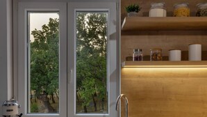 Eine Küche mit einem Fenster mit doppeltem Flügel, einem Spülbecken und einer Kaffeemaschine.