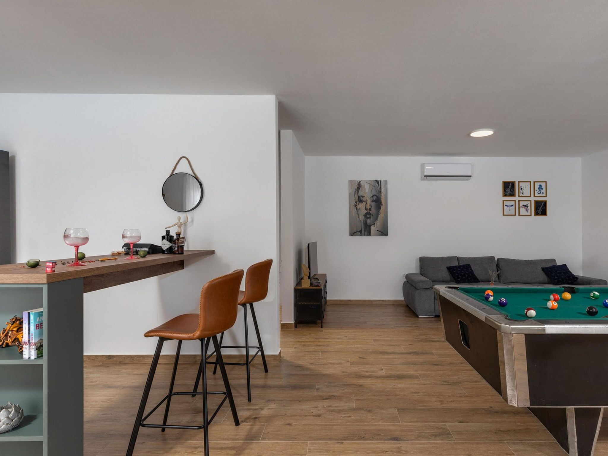 Ein modernes Wohnzimmer mit Billardtisch, einer Couch und einer Bar mit Sitzgelegenheiten.