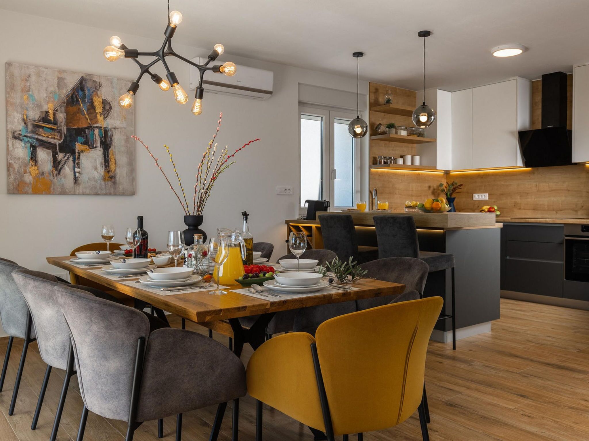 A modern kitchen with a central island, pendant lighting, and a dining area with a wooden table and chairs.