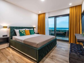 Ein modernes Hotelzimmer mit einem großen Bett, Meerblick und einem Balkon mit gelben Vorhängen.