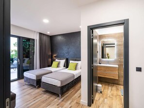 Quarto de hotel moderno com duas camas, uma janela grande e um banheiro com espelho e pia.