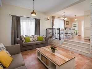 A modern living room with a sofa, a coffee table, and a dining area with chairs and a table. - Vacation home  by Interhome (Pridraga)