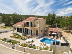 Ein zweistöckiges Haus mit Swimmingpool, Gartenmöbeln und einem Garten.