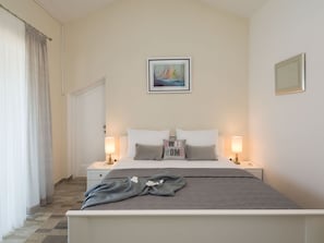 A hotel room with a bed, two bedside tables, a nightstand, a window with curtains, and a painting on the wall. - Vacation home  by Interhome (Pridraga)