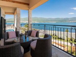 A balcony with wicker furniture, a glass table, and a view of the sea. - Beachfront villa Noa with heated pool by Interhome (Pridraga)