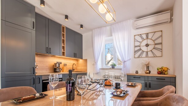 A modern kitchen with grey cabinets, a wooden countertop, and a dining area with a long table and brown chairs. - Villa Niko with heated pool by Interhome (Pridraga)