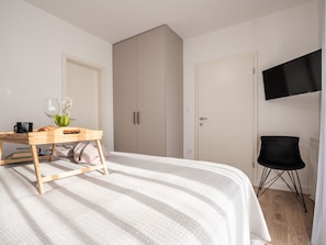 Ein Schlafzimmer mit Bett, Schreibtisch, Stuhl, Kleiderschrank und Fernseher.