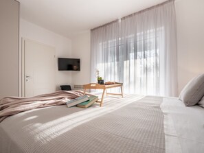 A bedroom with a bed, bedside table, books, a TV, and a window with curtains. - Villa Niko with heated pool by Interhome (Pridraga)