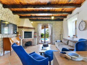 A cozy living room with a TV, fireplace, and outdoor view. - Villa Toscana Sole with pool by Interhome (Bokordici)