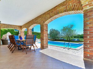 A covered patio with a pool, brick arches, and outdoor furniture. - Villa Toscana Sole with pool by Interhome (Bokordici)