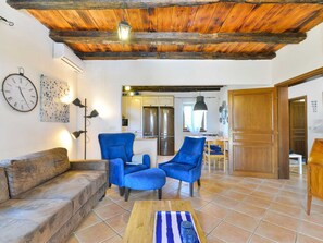 A living room with a rustic ceiling, a sofa, two armchairs, a coffee table, and a kitchen in the background. - Vacation home  by Interhome (Bokordici)