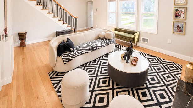 A spacious living room with a curved sofa, a round coffee table, a patterned rug, and a staircase. - Welcome to Seven Oaks:Your Home Away From Home (City of Orange)