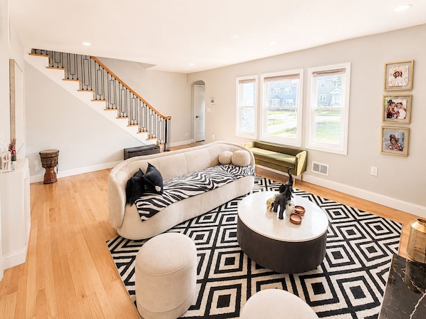 A spacious living room with a curved sofa, a round coffee table, a patterned rug, and a staircase. - Spacious 5-bedroom house in charming City of Orange with AC (City of Orange)