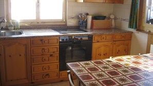 A kitchen with wooden cabinets, a stove, and a sink. - Casa Alpina und Fop Maiensäss, Waltensburg, (Waltensburg/Vuorz), 58011A by Interhome (Surselva)
