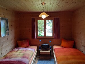A room with two beds, a window with curtains, a ceiling light, and a small table with a suitcase. - Casa Canal 27 Cavegn, Brigels, (Breil/Brigels), 65000B by Interhome (Breil/Brigels)