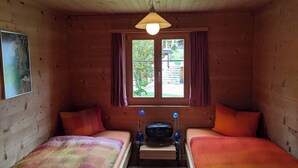 A cabin room with two beds, a window with curtains, a ceiling light, and a small table with a radio. - Casa Canal 27 Cavegn, Brigels, (Breil/Brigels), 65000B by Interhome (Breil/Brigels)