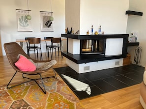 Ein modernes Wohnzimmer mit Kamin, einer Essecke mit Stühlen und einem Teppich.