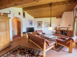A cozy living room with a fireplace, leather sofas, a television, and a rustic ceiling. - Casa Panorama Lutz, Brigels, (Breil/Brigels), 65061B by Interhome (Breil/Brigels)
