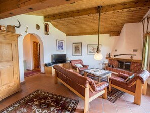 A cozy living room with a fireplace, leather sofas, a television, and a rustic wooden ceiling. - Casa Panorama Lutz, Brigels, (Breil/Brigels), 65061B by Interhome (Breil/Brigels)