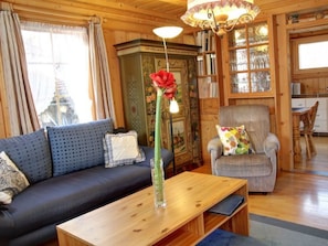 A cozy living room with a sofa, armchair, wooden coffee table, and a vase with a flower. - Ferienhaus Mulin Vegl Sprecher, Waltensburg, (Waltensburg/Vuorz), 58001B by Interhome (Vuorz)