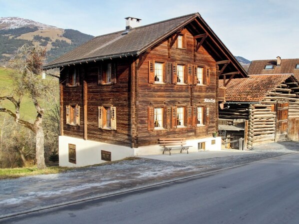 Eine Holzhütte mit geneigtem Dach, mehreren Fenstern mit Fensterläden und einem weißen Sockel.