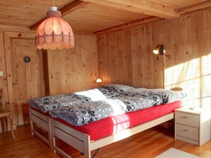A wooden-paneled room with a bed, bedside tables, and a hanging light fixture.